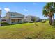 View of backyard with covered patio, lush lawn, and neighboring houses creating a suburban atmosphere at 32707 Tamarind Grove Ln, Wesley Chapel, FL 33543