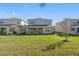 Spacious backyard with a covered patio, lush lawn, and a view of neighboring homes at 32707 Tamarind Grove Ln, Wesley Chapel, FL 33543