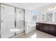 Bright bathroom showcasing glass enclosed shower, tub, dark wood vanity with double sinks, and a large mirror at 32707 Tamarind Grove Ln, Wesley Chapel, FL 33543