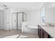 Bright bathroom featuring a glass-enclosed shower, soaking tub, and double vanity with dark wood cabinets at 32707 Tamarind Grove Ln, Wesley Chapel, FL 33543