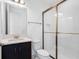 Modern bathroom features dark vanity, white tiled walls, toilet and shower with glass doors at 32707 Tamarind Grove Ln, Wesley Chapel, FL 33543