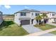 Beautiful two-story home with a two-car garage, paver driveway, and well-manicured lawn and palm trees at 32707 Tamarind Grove Ln, Wesley Chapel, FL 33543