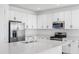 Close-up of an island kitchen featuring white cabinets, stainless steel appliances, and ample countertop space at 32707 Tamarind Grove Ln, Wesley Chapel, FL 33543