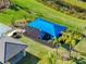 Aerial image of a playground shaded by a large blue awning alongside the clubhouse and tennis courts at 32707 Tamarind Grove Ln, Wesley Chapel, FL 33543