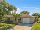 Front exterior view of a single-story house with a white garage door and landscaping at 5122 Lillilea Ln, New Port Richey, FL 34653