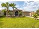Exterior view of a single-story house with a spacious lawn and palm trees at 10211 Cleghorn Dr, San Antonio, FL 33576