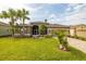 House exterior showcasing a well-maintained lawn, palm trees, and a paved driveway at 10211 Cleghorn Dr, San Antonio, FL 33576