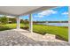 Covered patio with brick flooring providing views of the lake and well-manicured backyard at 11720 Renaissance Blvd, Venice, FL 34293