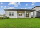 The backyard features green grass, a covered patio, and an open space, perfect for outdoor entertaining and relaxation at 1650 Fallon Pass, Zephyrhills, FL 33541
