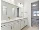 Bright bathroom with double sink vanity, large mirror, and a view to the adjacent bedroom at 1650 Fallon Pass, Zephyrhills, FL 33541
