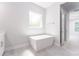 Modern bathroom featuring a freestanding tub, neutral tile flooring, and ample natural light from the window at 22426 Golden Retriever Ln, Brooksville, FL 34601