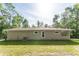 A side view of a one-story house with a patio and an AC unit, surrounded by grass and trees at 22426 Golden Retriever Ln, Brooksville, FL 34601