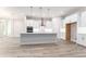 Well-lit open concept kitchen with white cabinets and a large island with stainless hood at 22426 Golden Retriever Ln, Brooksville, FL 34601