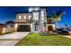 Modern home at twilight with manicured lawn, two-car garage, and high-end sportscar in the driveway at 2832 W Vina Del Mar Blvd, St Pete Beach, FL 33706