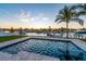 Backyard pool and spa with sunset sky, green grass and palm trees at 2832 W Vina Del Mar Blvd, St Pete Beach, FL 33706