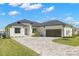 White one-story home with dark gray metal roof, paver driveway & landscaping at 1810 4Th E St, Palmetto, FL 34221