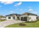 White one-story house with dark gray metal roof, paver driveway, and landscaping at 1810 4Th E St, Palmetto, FL 34221