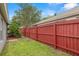 View of the fenced backyard with green grass and privacy, adjacent to the home's exterior at 30735 Lanesborough Cir, Wesley Chapel, FL 33543