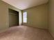 A simple bedroom features neutral walls, carpet flooring, closet, and natural light at 7140 Orchid Lake Rd, New Port Richey, FL 34653