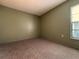 A carpeted bedroom features neutral walls, window, and natural light at 7140 Orchid Lake Rd, New Port Richey, FL 34653