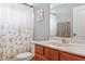 Clean bathroom with wood cabinets and floral shower curtain at 30552 Latourette Dr, Wesley Chapel, FL 33545