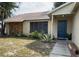 House exterior featuring a dark blue front door, stone accents, and well-maintained landscaping at 7140 Orchid Lake Rd, New Port Richey, FL 34653