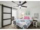 Cozy bedroom with decorative sliding barn door to bathroom, wood-look floors, ceiling fan, and beach-themed accents at 1906 2Nd St, Indian Rocks Beach, FL 33785