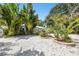 Single Gathering home featuring meticulous tropical landscaping with stone ground cover and a blue sky at 1906 2Nd St, Indian Rocks Beach, FL 33785