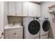 Laundry room with white cabinets, a utility sink, and a washer and dryer at 16240 Alpha Grove Pl, Odessa, FL 33556