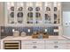 White kitchen cabinets with glass doors, blue hex tile backsplash, and quartz countertops at 16240 Alpha Grove Pl, Odessa, FL 33556