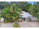 Aerial view of a charming house with lush landscaping, a metal roof, and a spacious driveway at 1906 2Nd St, Indian Rocks Beach, FL 33785