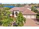 This waterfront home has a red tile roof, a brick driveway, and mature palm trees at 7925 Royal Queensland Way, Lakewood Ranch, FL 34202