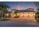 Stunning home features a tile roof, three-car garage, and lush landscaping with palm trees and paver driveway at 7925 Royal Queensland Way, Lakewood Ranch, FL 34202