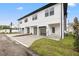 Modern townhome featuring a white exterior, black trim, garages, and a well-maintained lawn at 2709 W North B St # 1, Tampa, FL 33609