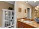 Bathroom vanity with granite countertops and decorative cabinet with glass shelving for storage at 17745 Gulf Blvd # 604, Redington Shores, FL 33708