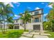 View of the front exterior of a home with a two-car garage, second story balcony and lush landscaping at 7949 2Nd S Ave, St Petersburg, FL 33707