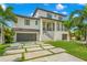 Elegant two-story waterfront home with a manicured lawn, walkway, and palm trees at 7949 2Nd S Ave, St Petersburg, FL 33707