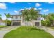 A modern two-story home shows curb appeal with lush landscaping, palm trees, and a well-maintained lawn at 7949 2Nd S Ave, St Petersburg, FL 33707