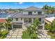 A modern home has a metal roof, attached garages, and a beautifully landscaped yard with palm trees and a walkway at 7949 2Nd S Ave, St Petersburg, FL 33707