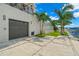 Modern home exterior with a gray garage door, paver driveway and tropical landscaping at 7949 2Nd S Ave, St Petersburg, FL 33707