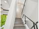 Modern staircase featuring sleek metal railings and natural wood steps leading upwards, bathed in soft, ambient lighting at 7949 2Nd S Ave, St Petersburg, FL 33707