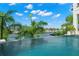 Breathtaking infinity pool overlooking the waterfront, framed by lush tropical landscaping and a clear blue sky at 7949 2Nd S Ave, St Petersburg, FL 33707