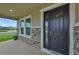 Home's exterior features a stone facade, covered porch, and dark-brown front door at 8277 Bower Bass Cir, Wesley Chapel, FL 33545