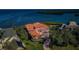 Aerial view of a beautiful house with an orange tile roof, a manicured lawn, and views of the ocean at 3418 Braeside Pl, Clearwater, FL 33759