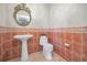 Bathroom showcasing a pedestal sink, terracotta tile, decorative mirror and updated fixtures at 3418 Braeside Pl, Clearwater, FL 33759