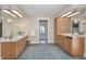 Bathroom boasts dual vanities with mirrors, storage, and a charming view of the hallway and exterior at 3418 Braeside Pl, Clearwater, FL 33759