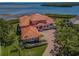 Sprawling waterfront property featuring a clay tile roof, circular driveway, and tropical landscaping at 3418 Braeside Pl, Clearwater, FL 33759