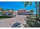 Inviting Mediterranean-style home featuring a brick driveway, three-car garage, and lush landscaping at 3418 Braeside Pl, Clearwater, FL 33759