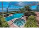 Screened pool and spa with tropical plants and a view of the water at 3418 Braeside Pl, Clearwater, FL 33759