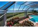 Enclosed pool area with water view, tropical plants, red brick decking and clear blue sky at 3418 Braeside Pl, Clearwater, FL 33759